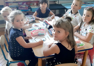 Dzieci rysują przy stolikach.